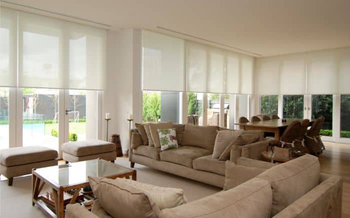 Motorised Blinds & Roller Blinds Melbourne - a room with large brown couches, side tables and large windows