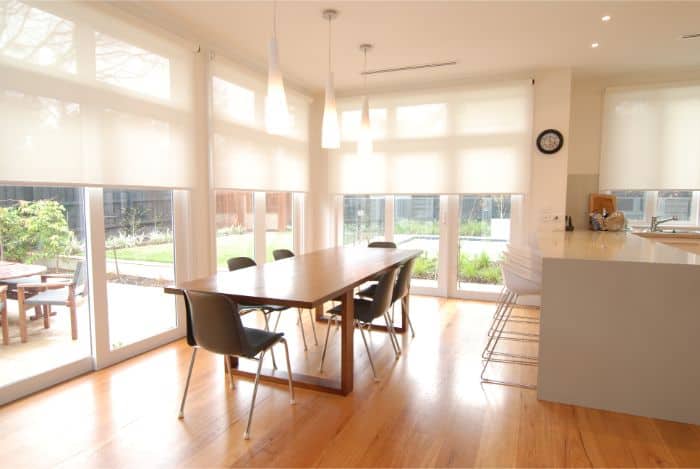Motorised Blinds & Roller Blinds Melbourne - a large wooden dining table with six chairs and spacious windows