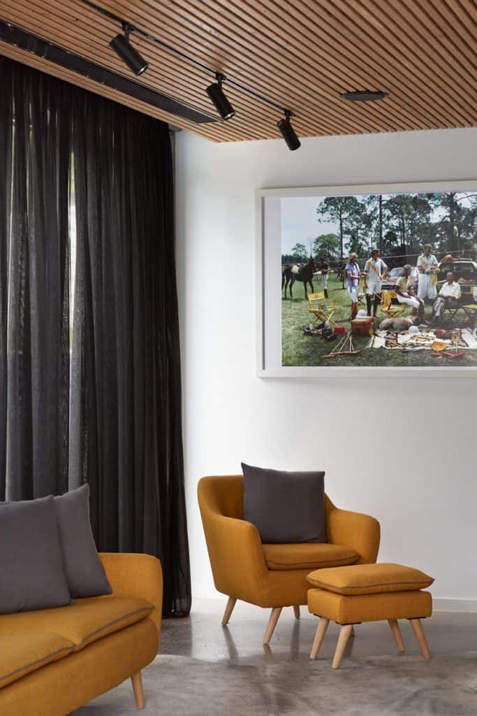 Roman Blinds & Curtains Melbourne - a room with a couch and chairs, ottoman and framed picture on the wall
