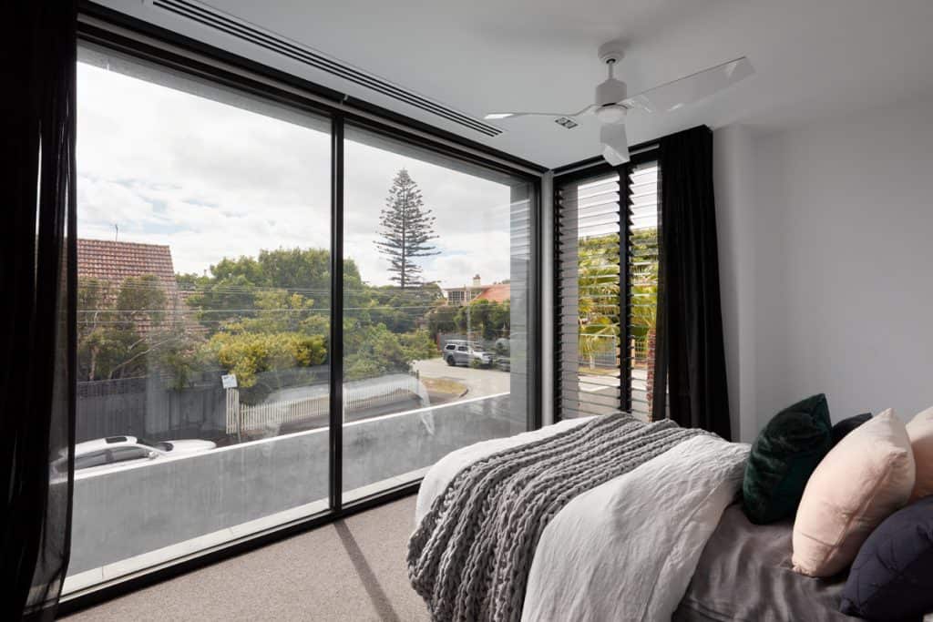 Roman Blinds & Curtains Melbourne - a bedroom with white walls, large windows framed by black curtains
