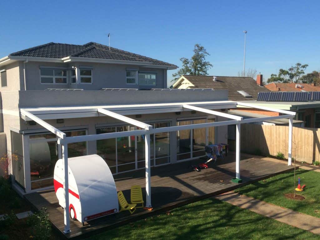 Folding Arm Awnings & Markilux Awnings Stockist - a view of a house with an open awning and wooden deck