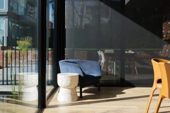 Motorised Blinds & Roller Blinds Melbourne - a blue chair and side table with black blinds dropping to the floor