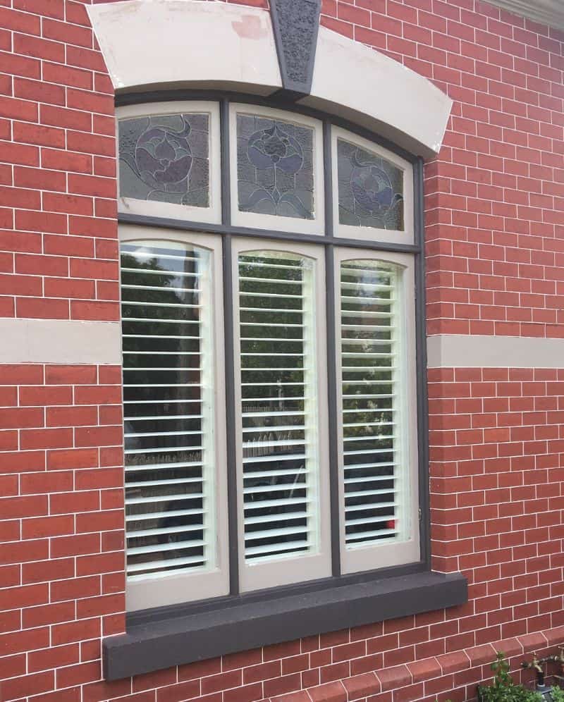 Plantation shutters - side angle of plantation shutters as viewed from the outside on a brick home