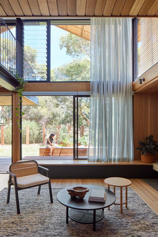 Twp storey window with window seat and open sheer curtain looking out into garden