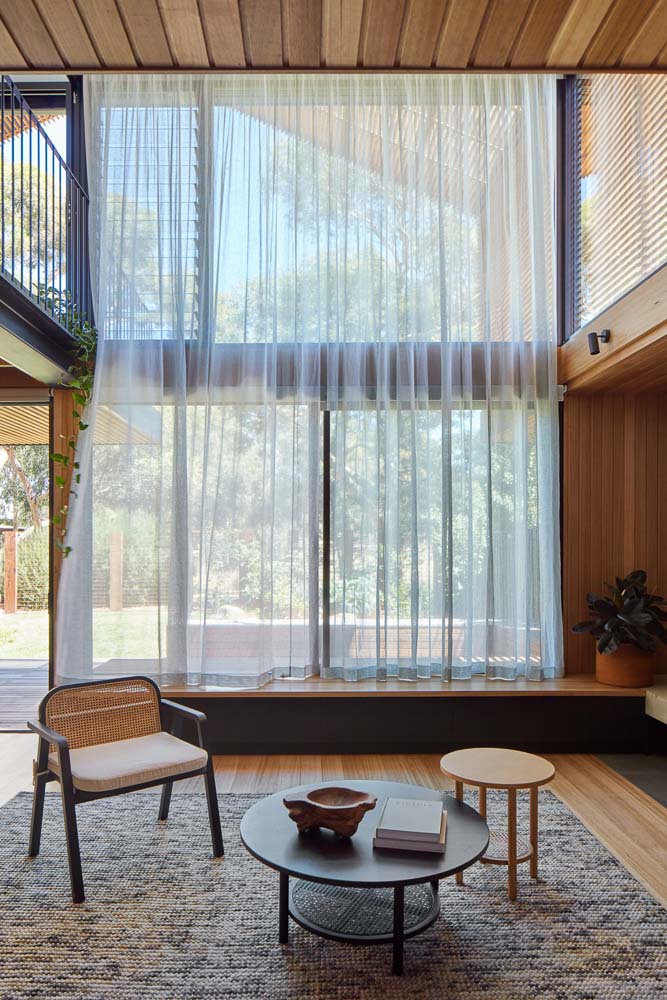 Two storey space with full height sheer curtains billowing in breeze