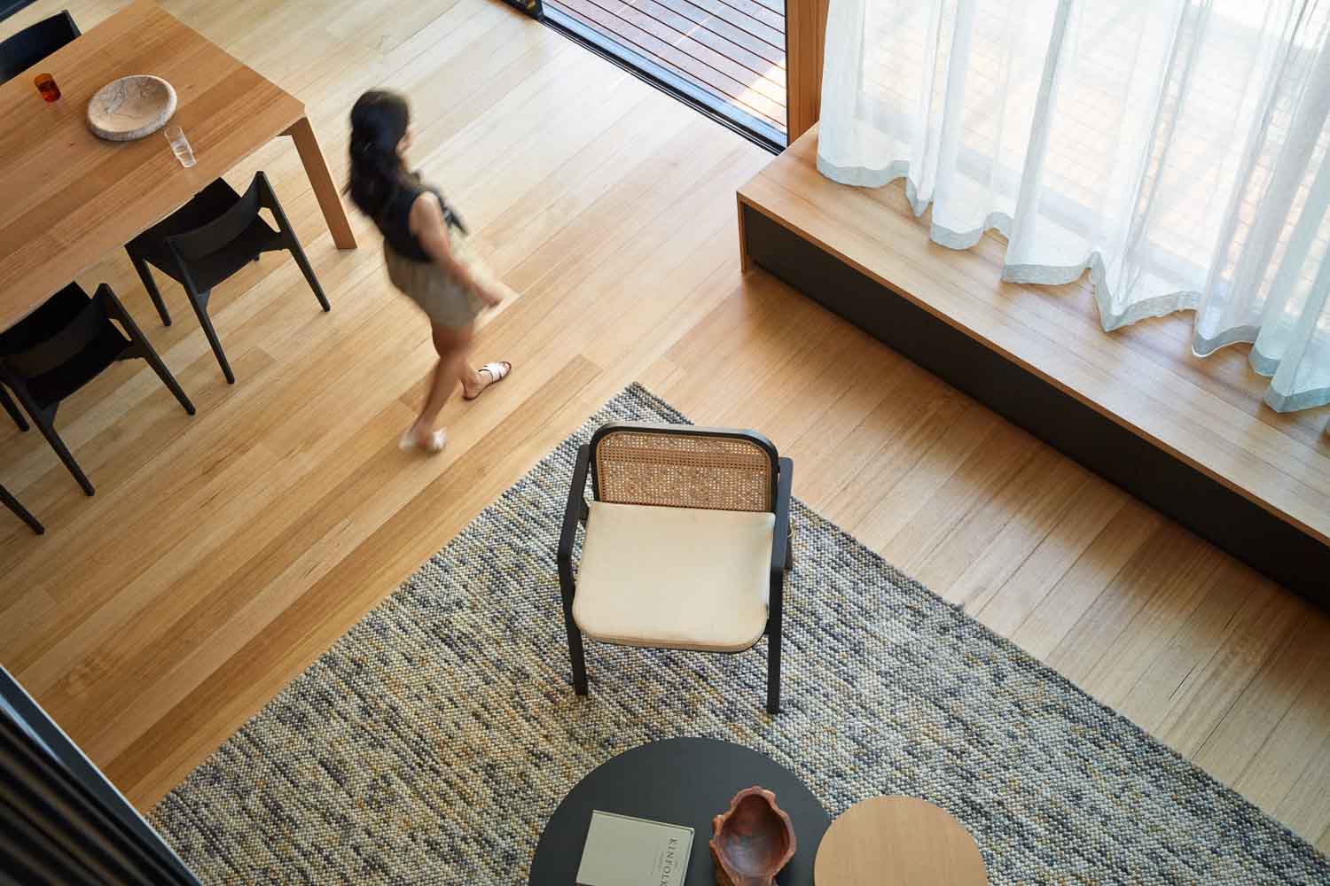 Looking down into living space with timber flooring and sheer curtains from void above