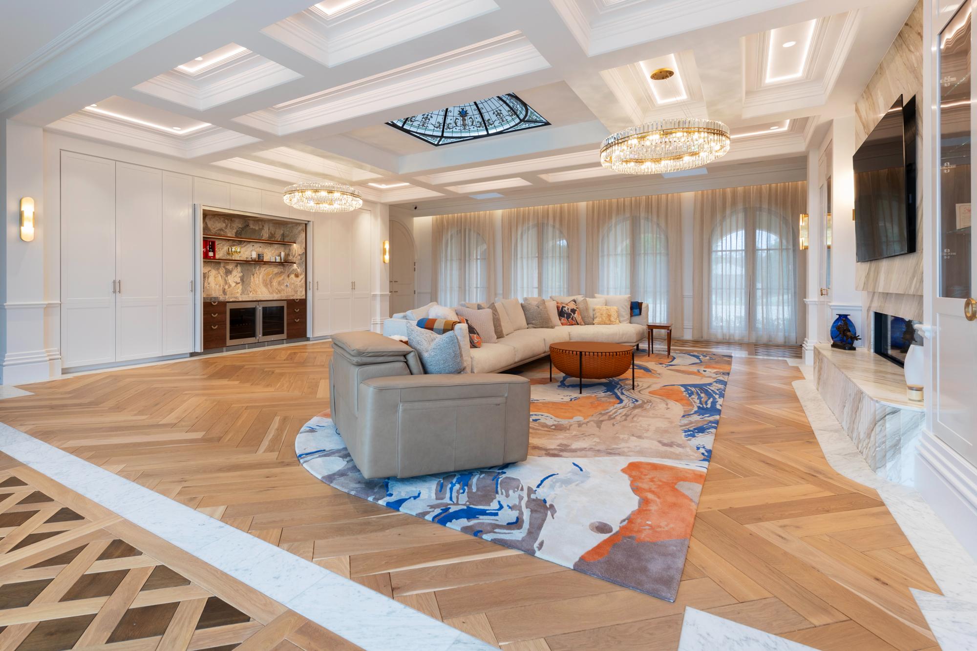 Floor-to-ceiling sheer curtains in a luxury living room with parquetry flooring and large modern floor rug and sofa