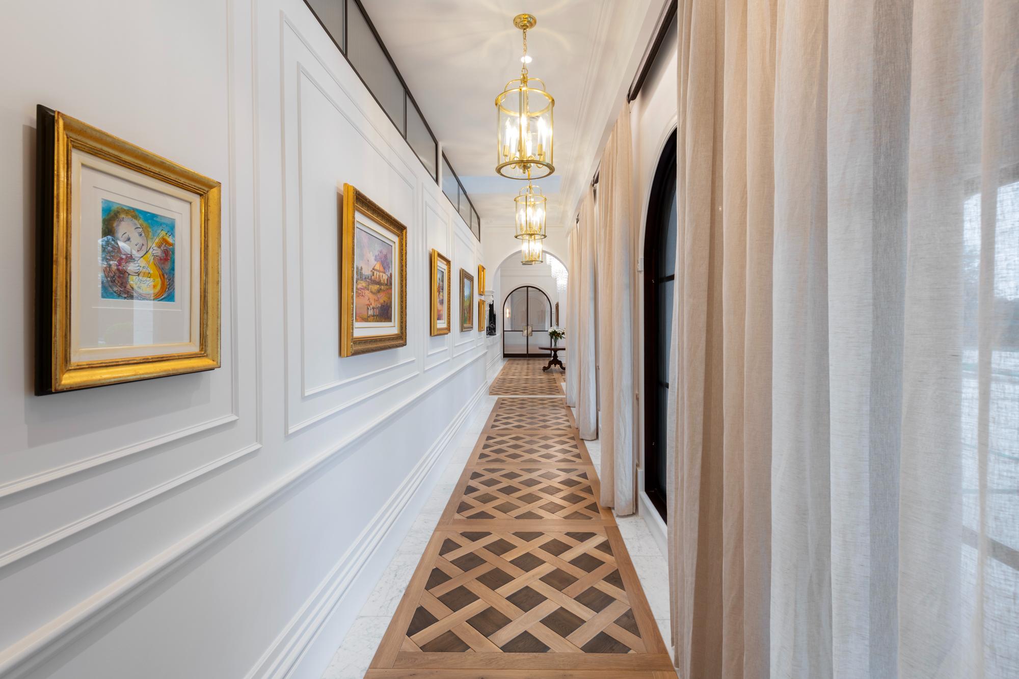 Long Hallway with wainscoting on one side and windows on the other parquetry floor, sheer curtains and motorised SOM60 blinds concealed in built in pelmets