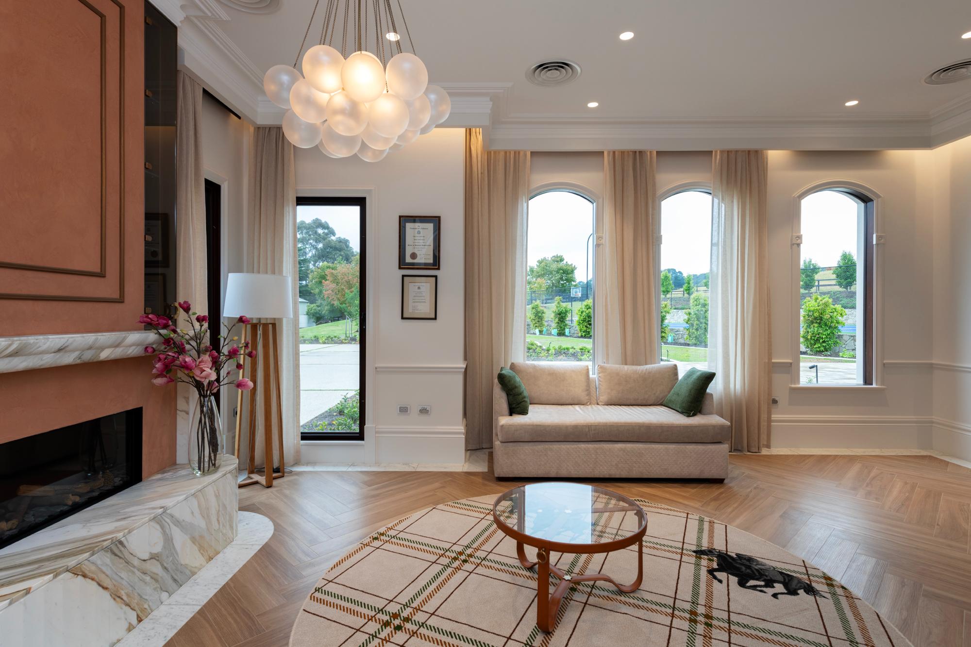 Luxury livingroom with built in curtain pelmet with concealed lighting and floor to ceiling sheer curtains and parquetry flooring looking out into landscaped garden