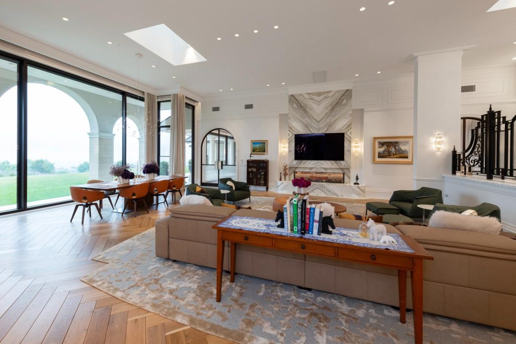 Living and dining space with large windows looking out into landscape with open sheers framing windows.