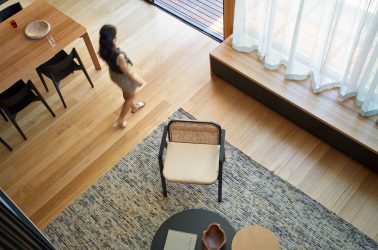 Looking down into living space with timber flooring and sheer curtains from void above